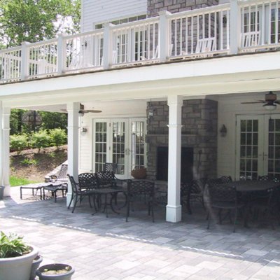 covered paved patio with new deck over a stone fireplace