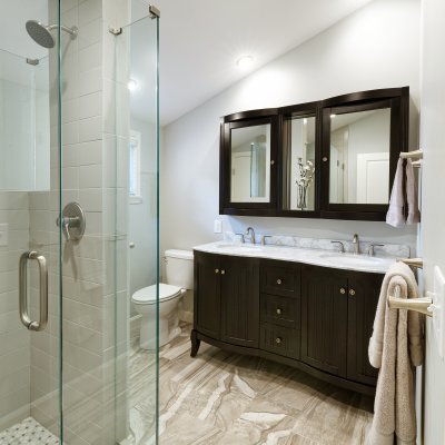 Bathroom with glass shower, black vanity, and mirror sloped ceiling   